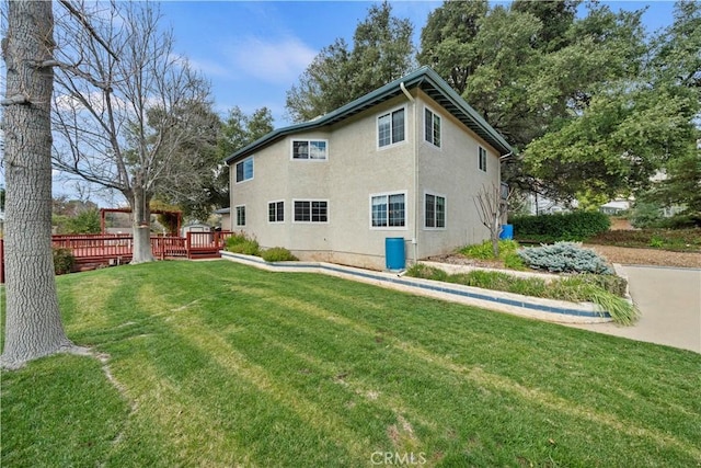 back of property with a yard, a deck, and stucco siding