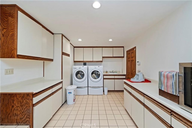 laundry area featuring cabinet space, light tile patterned floors, washer and clothes dryer, a sink, and recessed lighting