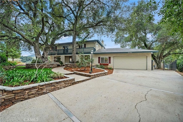 traditional-style house with driveway, a balcony, an attached garage, and stucco siding