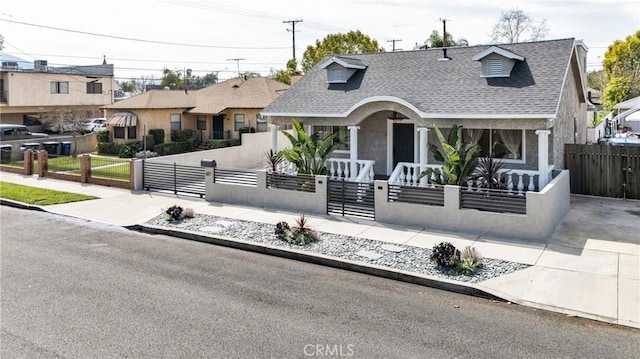 view of front of home with a fenced front yard, roof with shingles, covered porch, and a gate