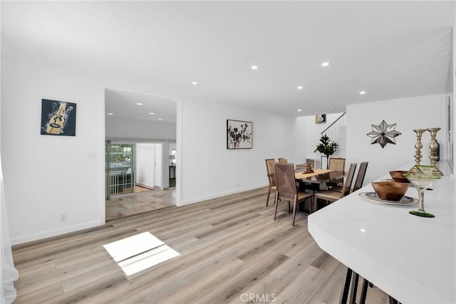 dining space with stairs, recessed lighting, light wood-type flooring, and baseboards