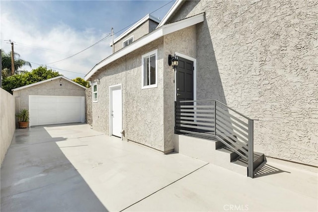 view of side of property with an outdoor structure, a garage, and stucco siding