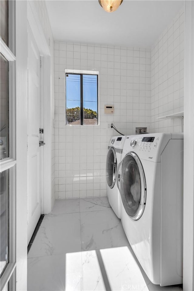 washroom featuring washer and dryer, laundry area, tile walls, and marble finish floor