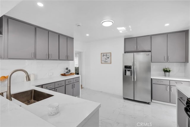 kitchen with marble finish floor, gray cabinetry, a sink, stainless steel fridge with ice dispenser, and light countertops