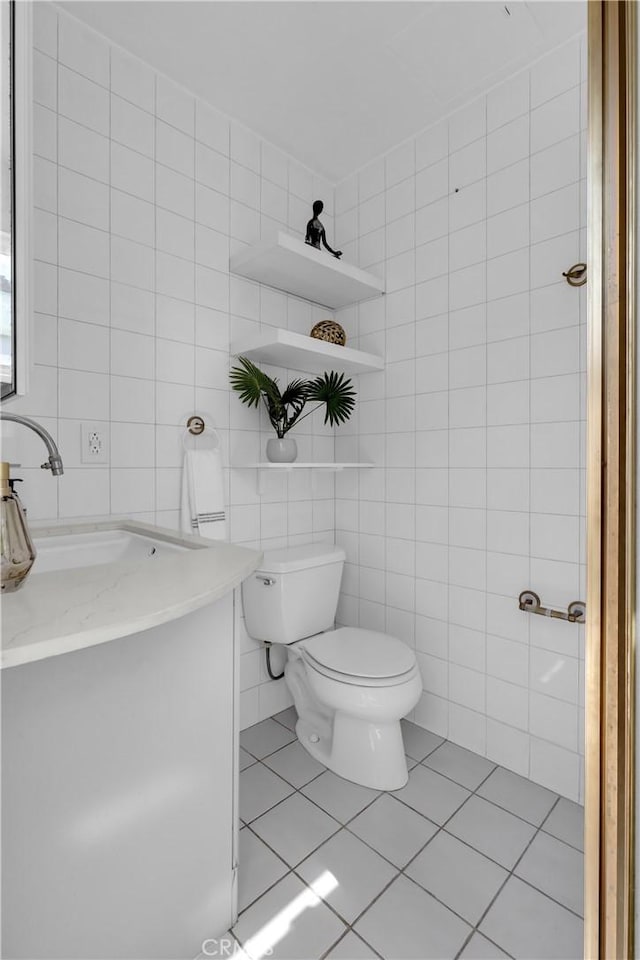 bathroom with tile patterned floors, toilet, tile walls, and vanity