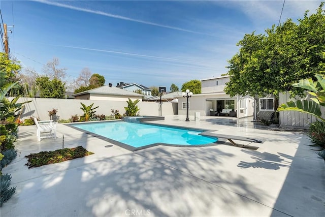 view of swimming pool featuring a patio, a pool with connected hot tub, a fenced backyard, and a diving board