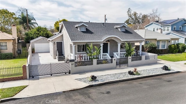 view of front facade featuring a detached garage, a porch, concrete driveway, and a fenced front yard