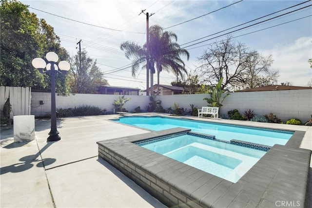 view of swimming pool with a diving board, a pool with connected hot tub, a fenced backyard, and a patio area