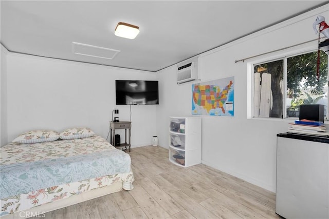 bedroom featuring attic access, a wall unit AC, and wood finished floors