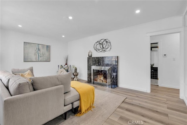 living area featuring a fireplace, light wood-style flooring, recessed lighting, and baseboards