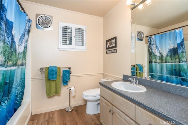 bathroom featuring toilet, wood finished floors, vanity, baseboards, and crown molding