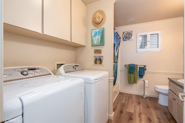 clothes washing area featuring laundry area, washing machine and dryer, light wood-style flooring, and baseboards