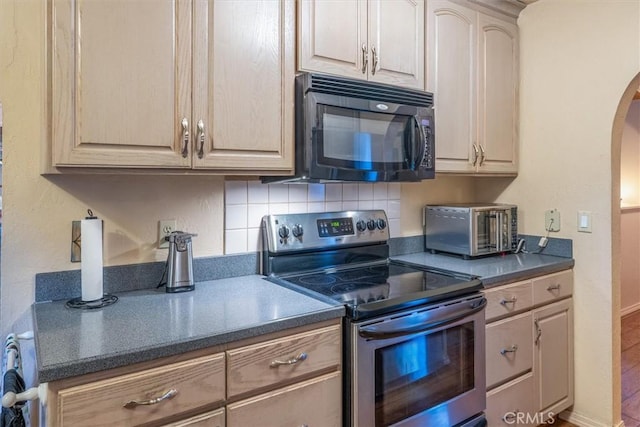 kitchen with arched walkways, decorative backsplash, dark countertops, stainless steel range with electric stovetop, and black microwave