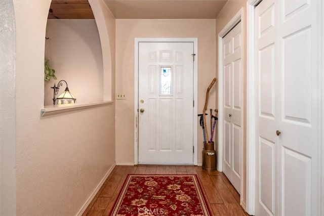 doorway featuring baseboards and wood finished floors