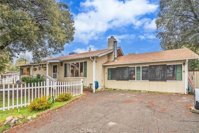 single story home featuring a fenced front yard and a chimney