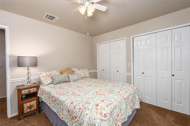 carpeted bedroom featuring ceiling fan, visible vents, and two closets