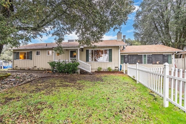 single story home featuring fence private yard, a chimney, a sunroom, and a front yard