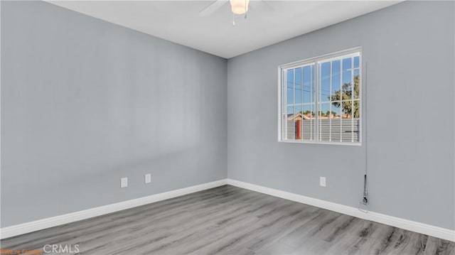 empty room featuring wood finished floors, a ceiling fan, and baseboards