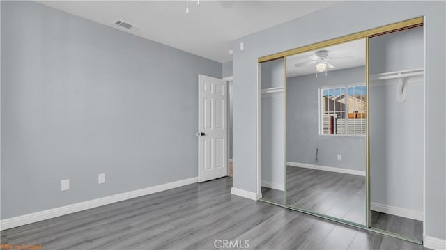 unfurnished bedroom featuring baseboards, visible vents, a ceiling fan, wood finished floors, and a closet