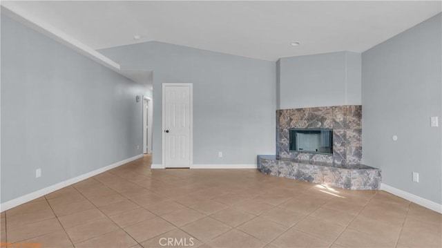 unfurnished living room featuring lofted ceiling, a fireplace, baseboards, and tile patterned floors