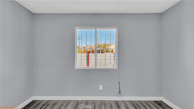 spare room featuring wood finished floors and baseboards