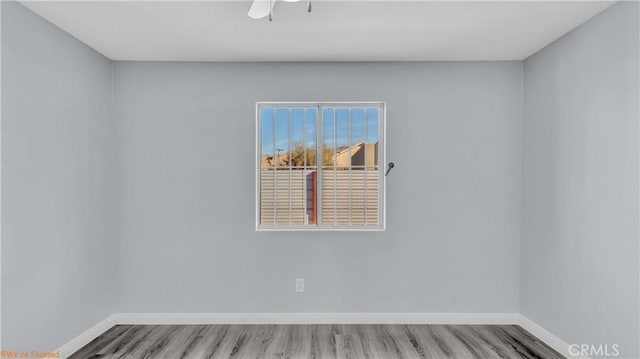 spare room featuring ceiling fan, wood finished floors, and baseboards