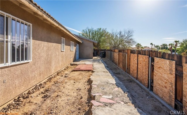 view of side of home featuring a tile roof, fence, and stucco siding