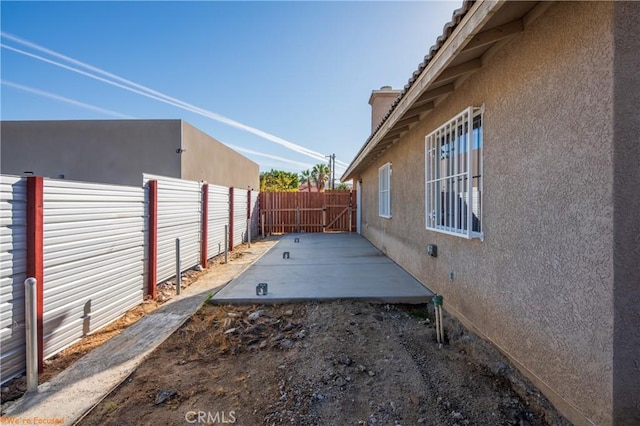 view of side of home with a fenced backyard, a patio, and stucco siding