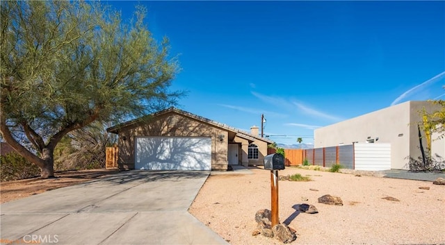 view of front facade with stucco siding, driveway, an attached garage, and fence