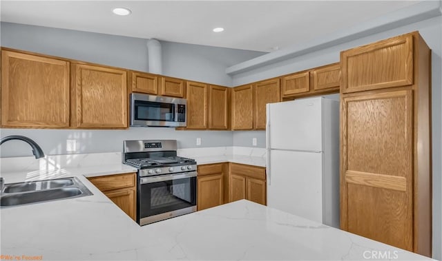 kitchen featuring brown cabinetry, appliances with stainless steel finishes, light stone countertops, a sink, and recessed lighting