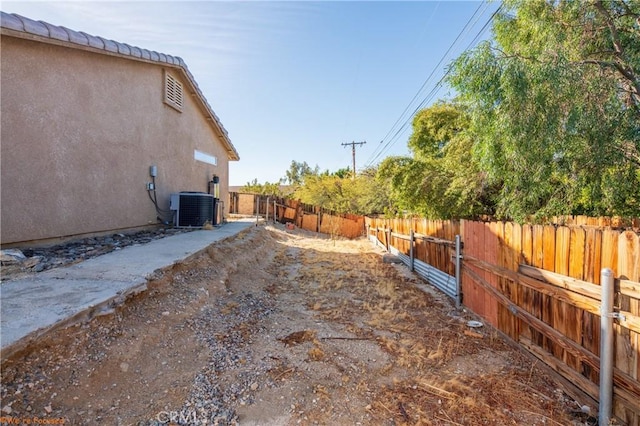 view of yard featuring central AC and fence