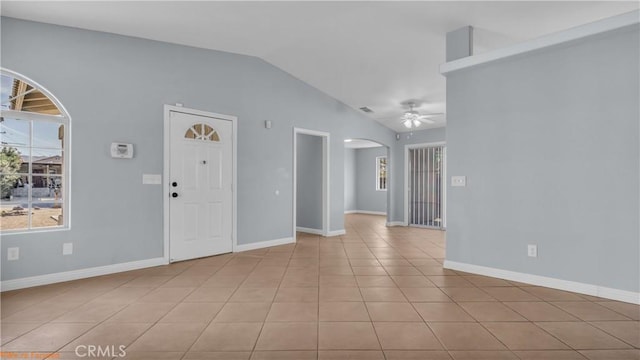 interior space featuring arched walkways, light tile patterned floors, vaulted ceiling, ceiling fan, and baseboards