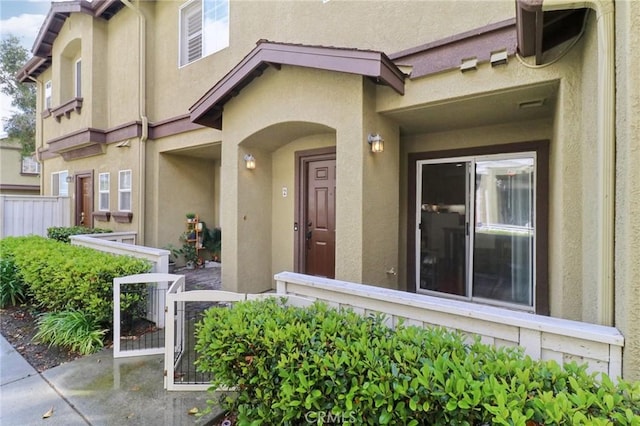 doorway to property with fence and stucco siding