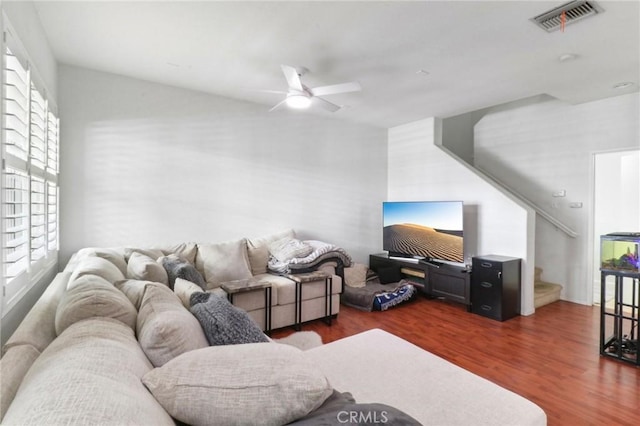 living room featuring stairway, ceiling fan, visible vents, and wood finished floors