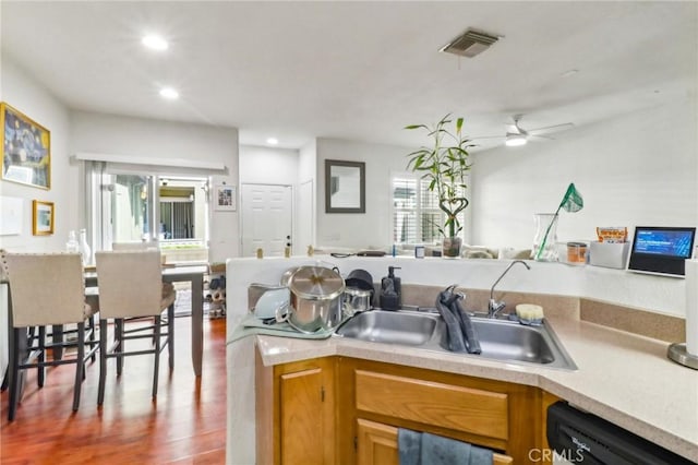 kitchen with wood finished floors, a sink, visible vents, light countertops, and dishwasher