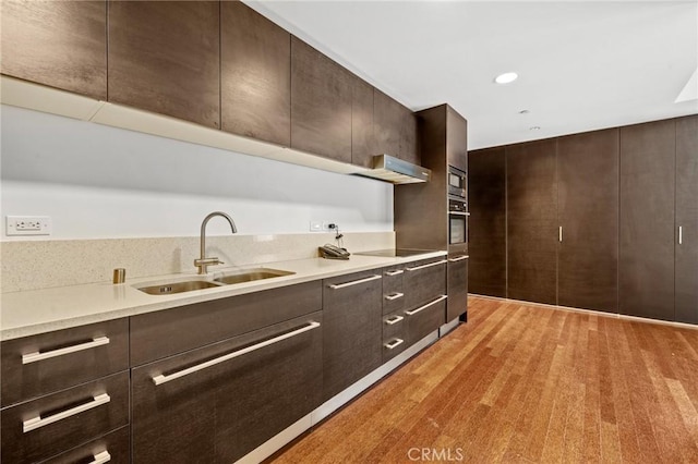 kitchen with modern cabinets, dark brown cabinets, and a sink