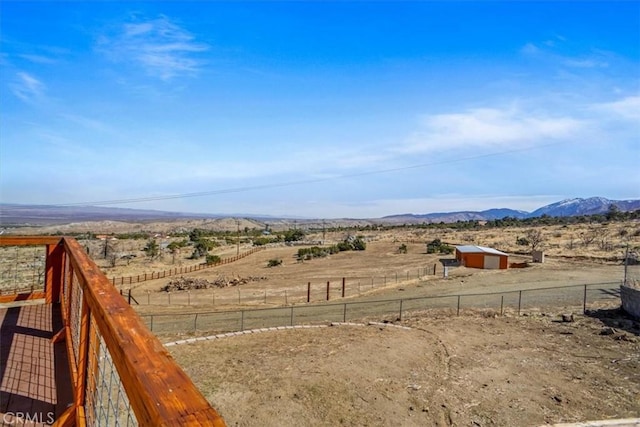 view of yard featuring a rural view, an outdoor structure, fence, and a mountain view