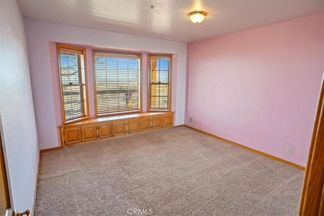 unfurnished room featuring carpet, baseboards, and a textured ceiling