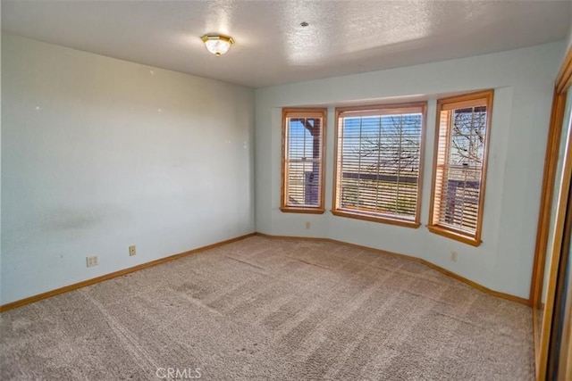 unfurnished room featuring baseboards, a textured ceiling, and light colored carpet