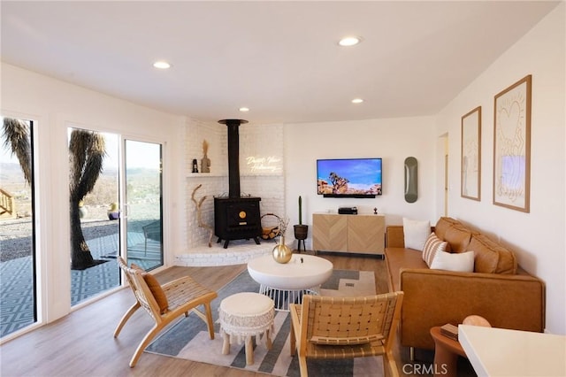 living room with wood finished floors, a wood stove, and recessed lighting