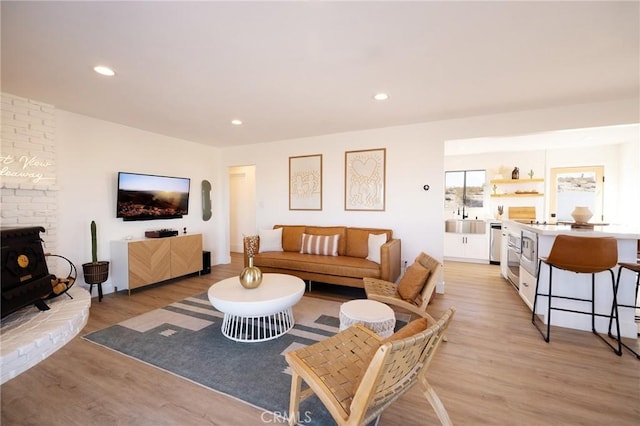 living area with light wood-type flooring, a wood stove, and recessed lighting