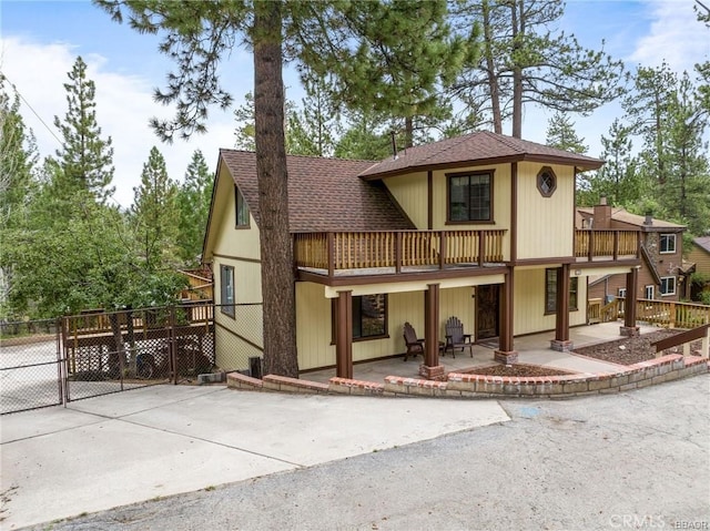 view of front of home with roof with shingles, a patio area, fence, and a gate