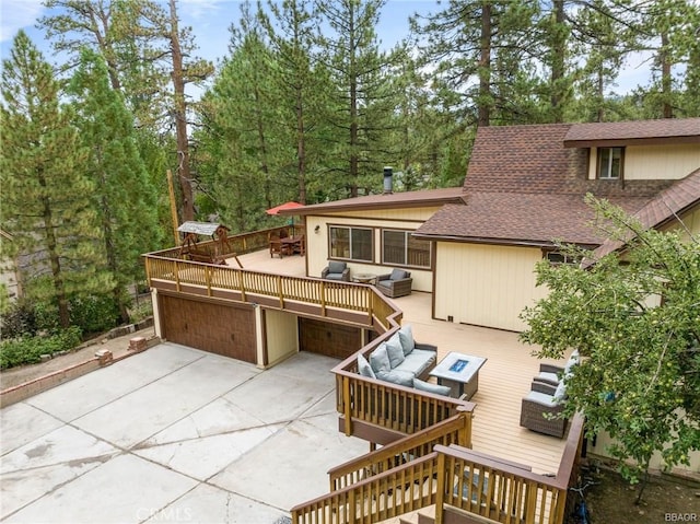 exterior space featuring a garage, driveway, a deck, and an outdoor living space with a fire pit