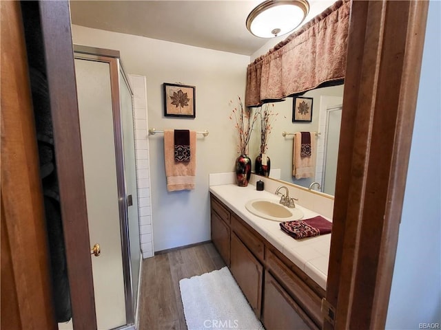 bathroom featuring a stall shower, wood finished floors, and vanity