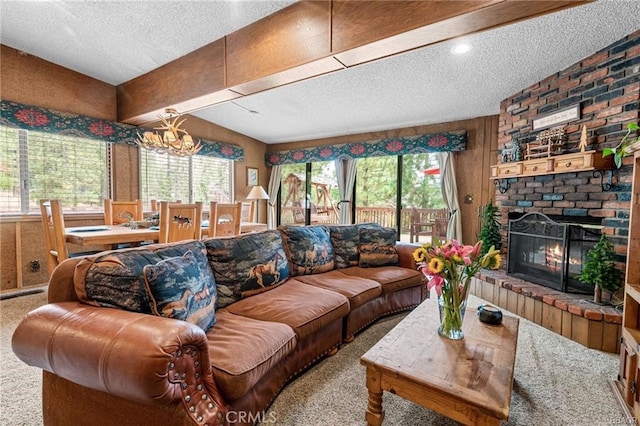 living room with a brick fireplace, carpet flooring, a notable chandelier, and a textured ceiling