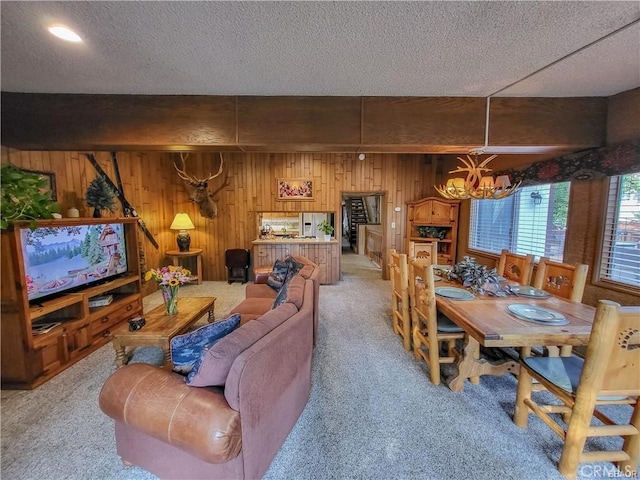 living area with a chandelier, light carpet, and a textured ceiling