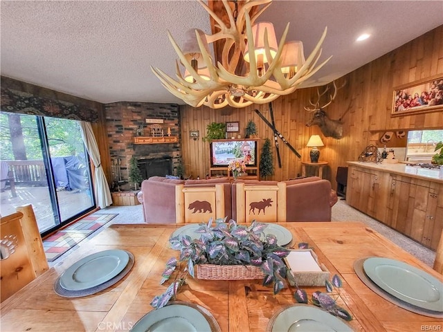 dining area with wooden walls, a fireplace, and a textured ceiling