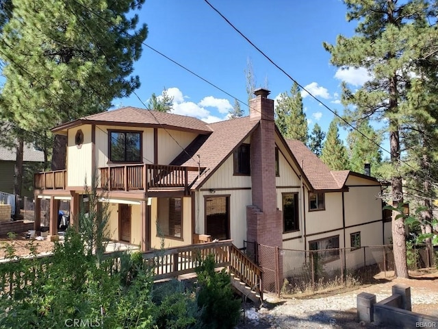 back of property featuring a balcony, a chimney, fence, and roof with shingles