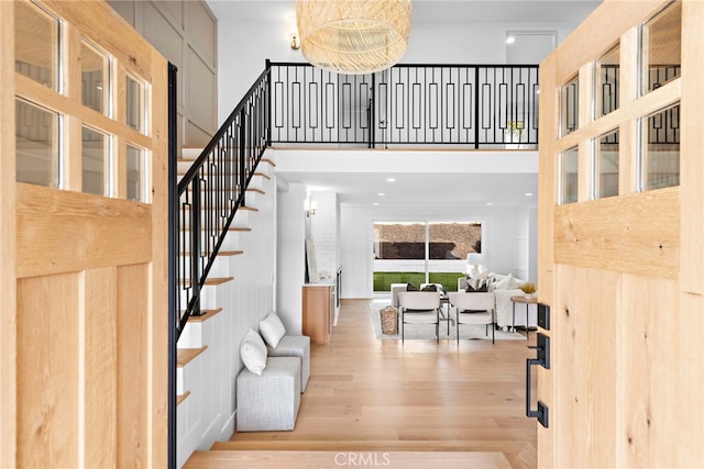 foyer entrance featuring stairway, a towering ceiling, and wood finished floors