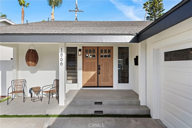 view of exterior entry featuring a shingled roof